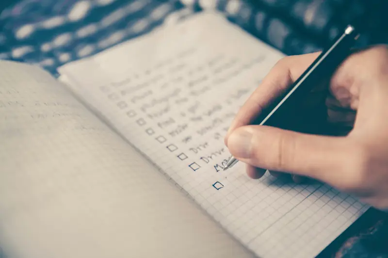 Hand writing a checklist in a notebook - planning food tracking without ads or distractions